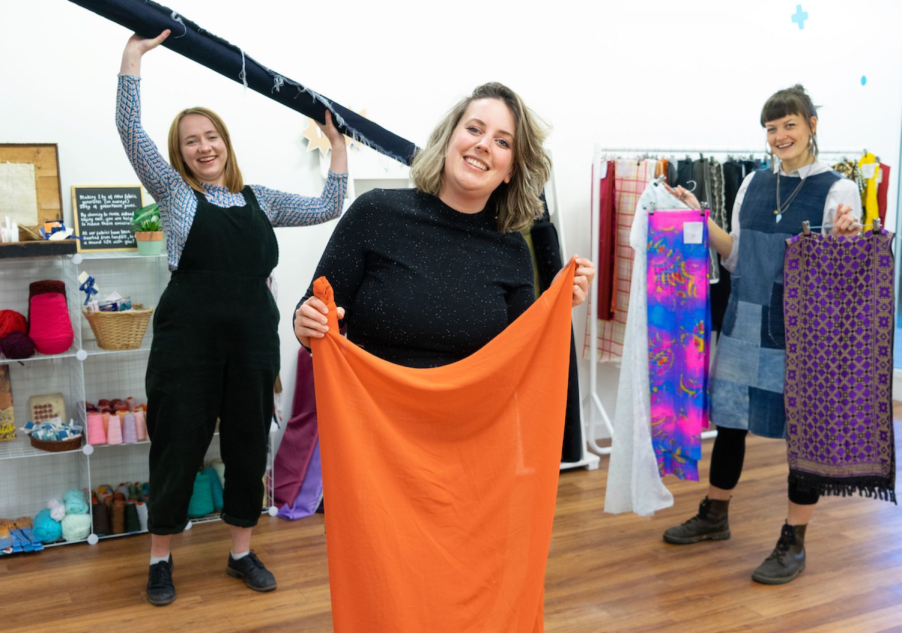 A group of staff holding second hand clothes